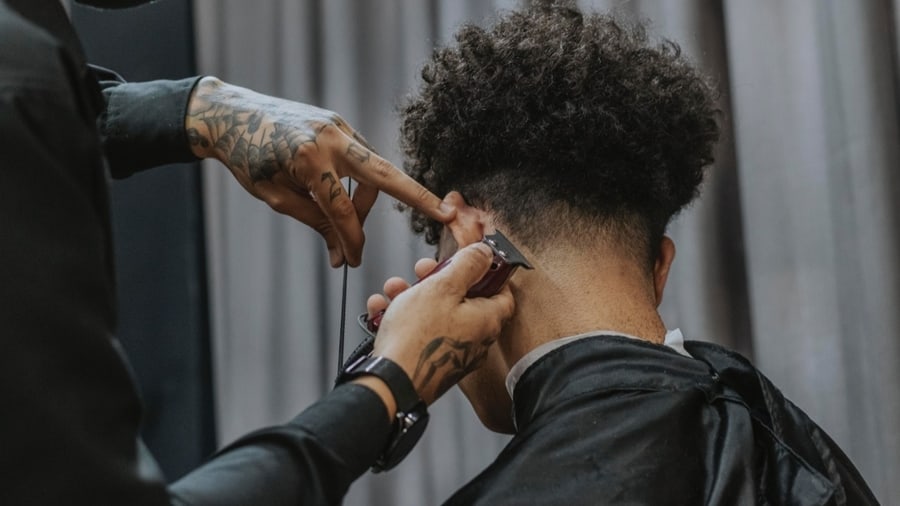 A barber lining up curly hair 