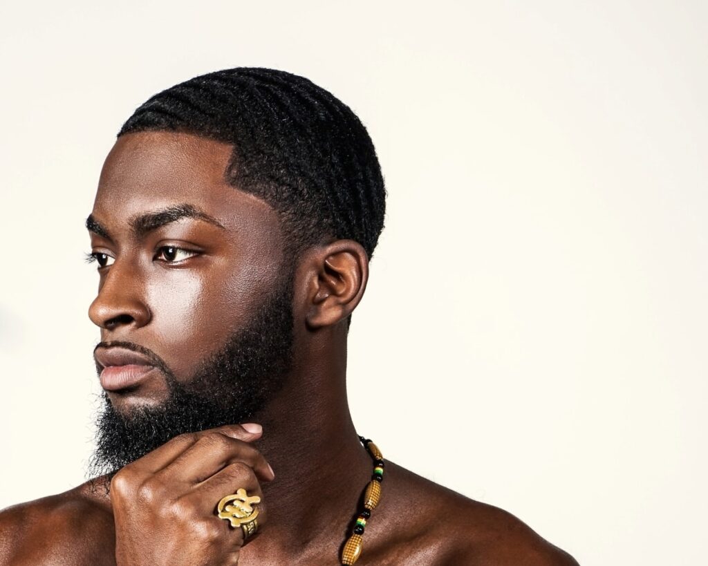 A handsome black man softening his beard with some beard products
